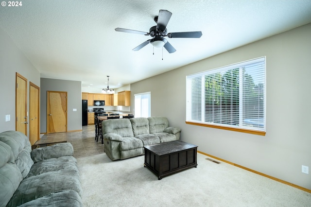 living room featuring a textured ceiling and ceiling fan with notable chandelier