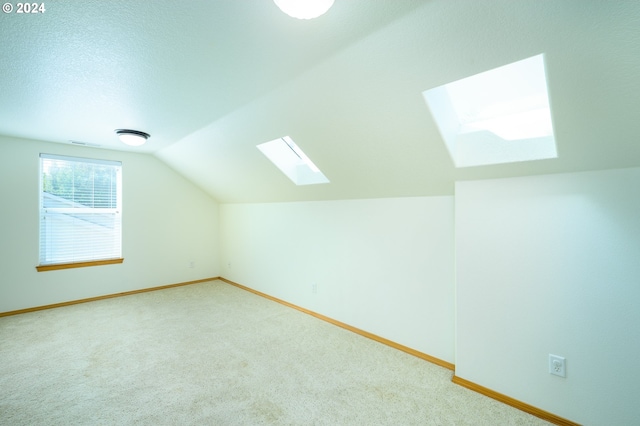 additional living space featuring lofted ceiling with skylight and carpet