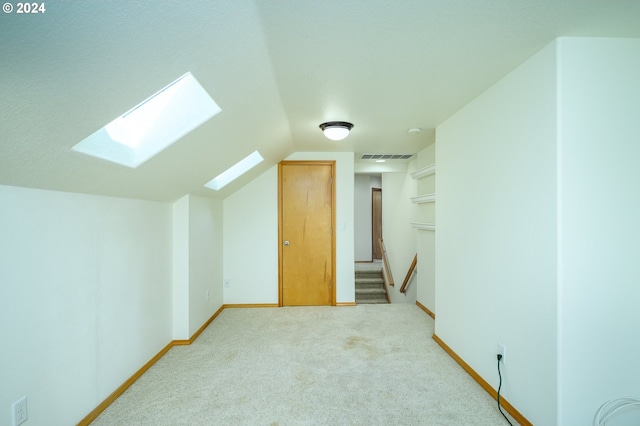 additional living space with vaulted ceiling with skylight and carpet flooring