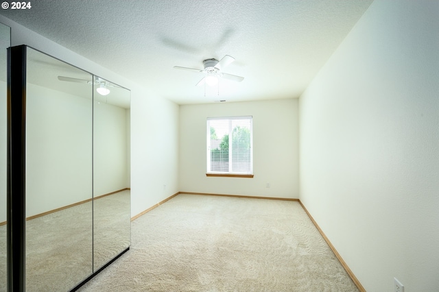 carpeted spare room featuring a textured ceiling and ceiling fan