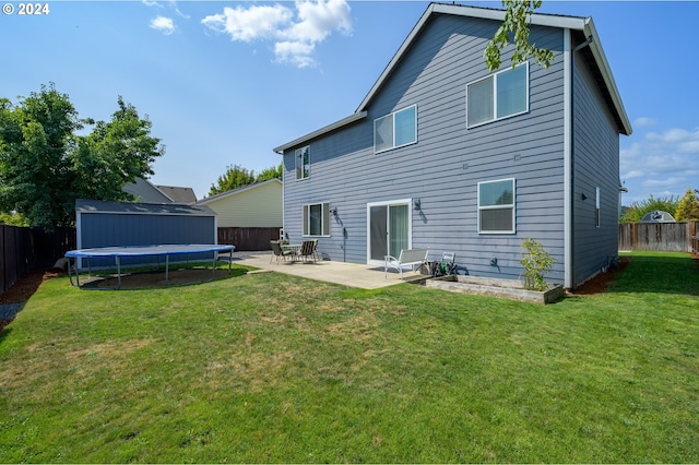 back of property featuring a storage shed, a patio area, a yard, and a trampoline