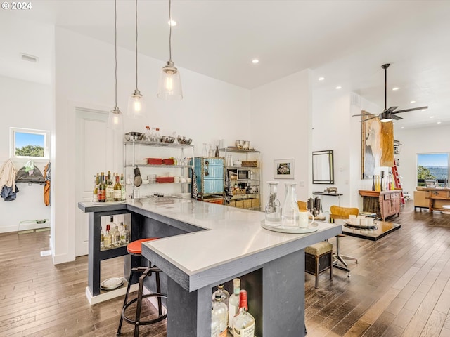 kitchen featuring wood finished floors, visible vents, recessed lighting, hanging light fixtures, and a kitchen bar