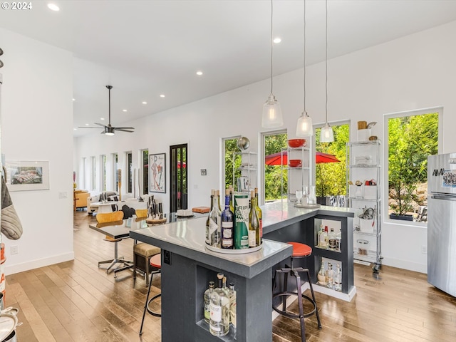 kitchen featuring hardwood / wood-style floors, recessed lighting, freestanding refrigerator, and a breakfast bar