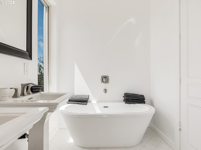 full bathroom featuring tile patterned floors, baseboards, a soaking tub, and a sink