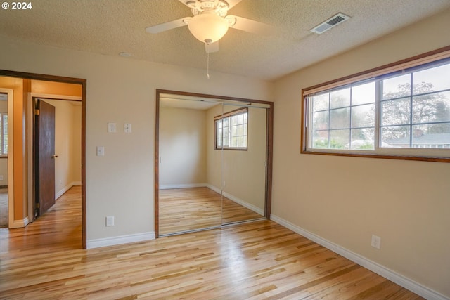 unfurnished bedroom featuring ceiling fan, light hardwood / wood-style floors, a closet, and a textured ceiling