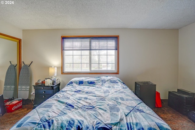 bedroom featuring a textured ceiling and dark colored carpet