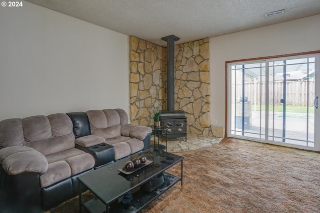 living room featuring carpet flooring, a textured ceiling, and a wood stove