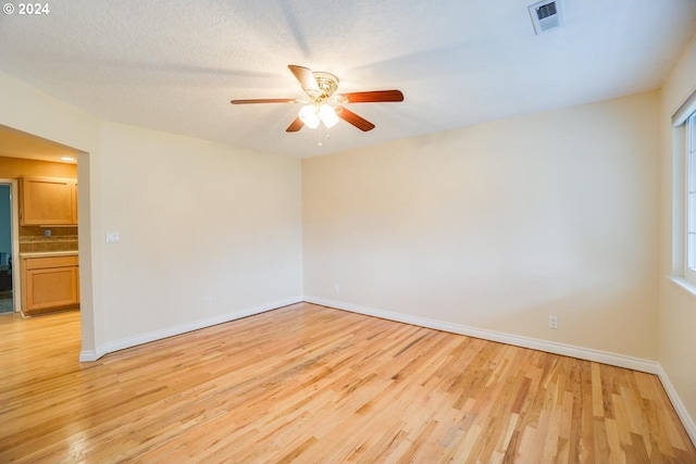 unfurnished room featuring light wood-type flooring, ceiling fan, and a textured ceiling