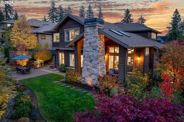 property exterior at dusk featuring a patio and a lawn