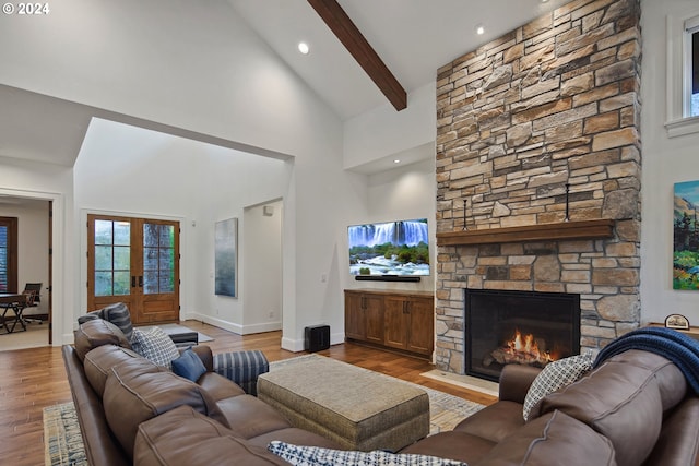 living room with french doors, light wood-type flooring, high vaulted ceiling, beamed ceiling, and a stone fireplace