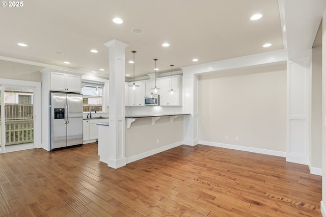 kitchen featuring a kitchen bar, light wood finished floors, recessed lighting, and stainless steel appliances