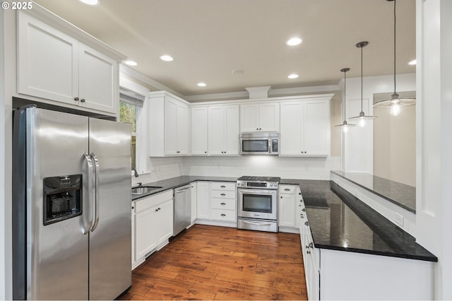 kitchen with a peninsula, dark wood finished floors, white cabinetry, stainless steel appliances, and backsplash