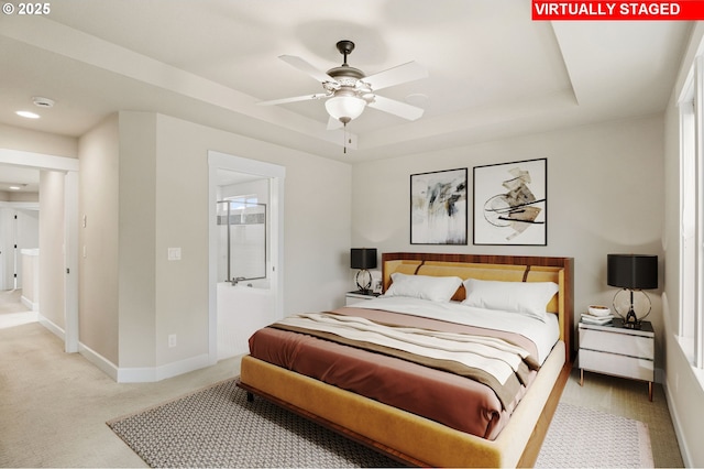 bedroom featuring a tray ceiling, baseboards, and light colored carpet
