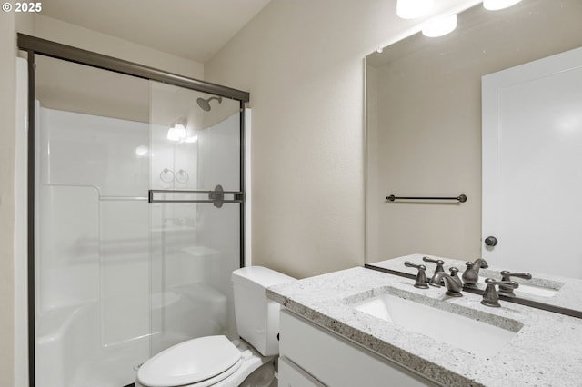 bathroom featuring toilet, vanity, and a stall shower