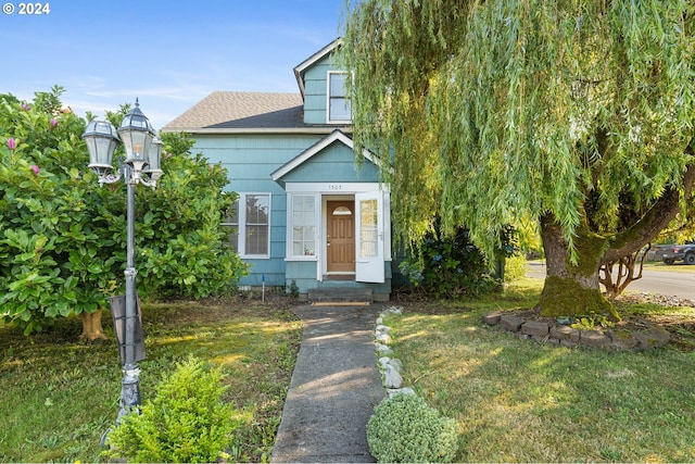 view of front of home featuring a shingled roof and a front yard