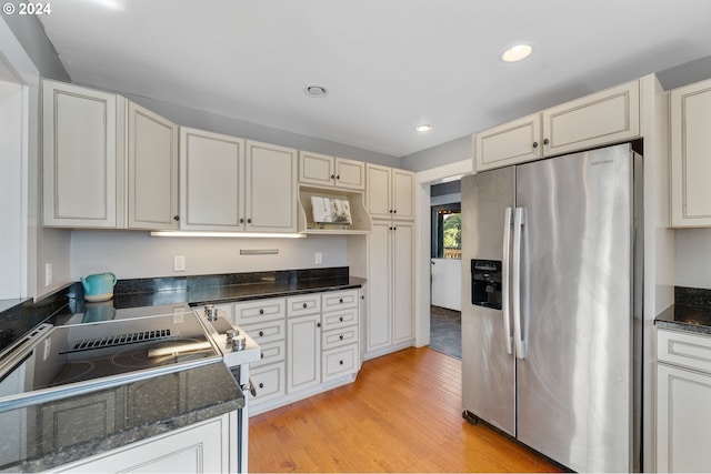 kitchen featuring light wood-type flooring, dark stone counters, and stainless steel refrigerator with ice dispenser