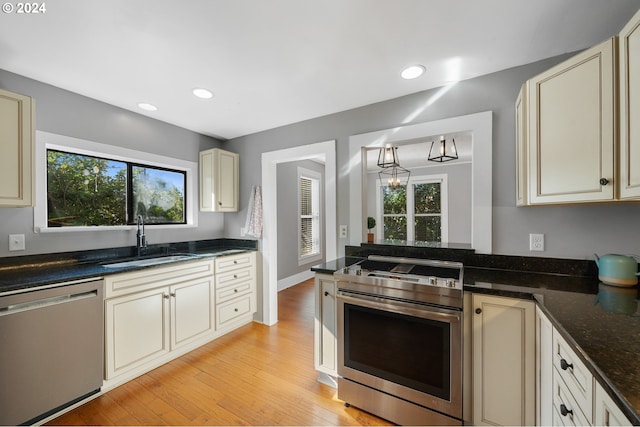 kitchen with light hardwood / wood-style flooring, cream cabinets, stainless steel appliances, and sink