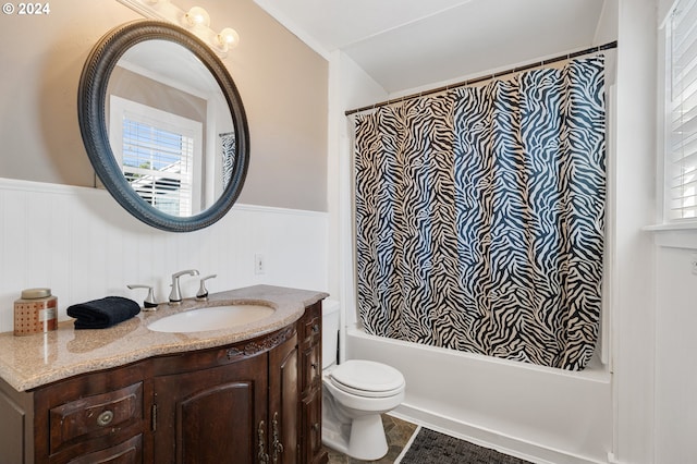 bathroom with a wainscoted wall, toilet, vanity, and shower / tub combo