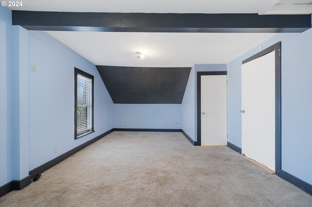 carpeted empty room with vaulted ceiling with beams