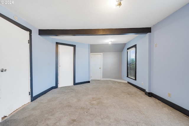 unfurnished room featuring light carpet and lofted ceiling with beams