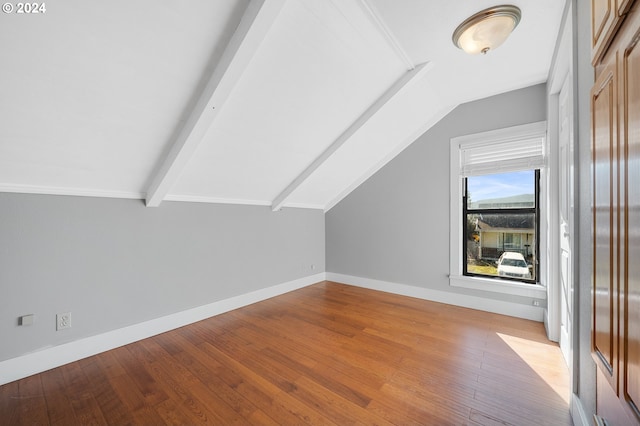 additional living space featuring wood-type flooring and lofted ceiling with beams