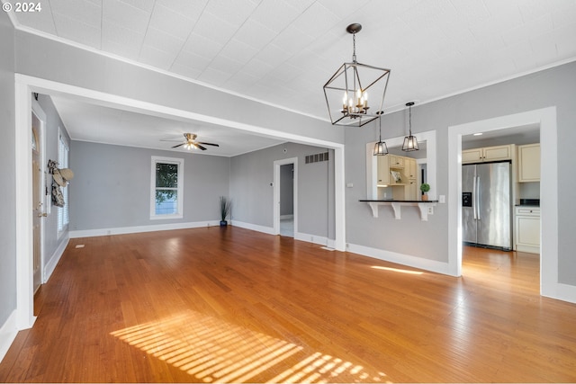 unfurnished living room featuring ceiling fan with notable chandelier and light wood-type flooring