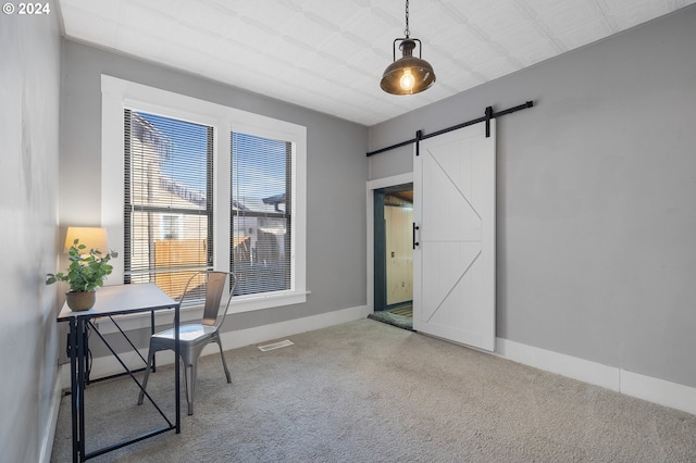 carpeted home office featuring a barn door, visible vents, and baseboards