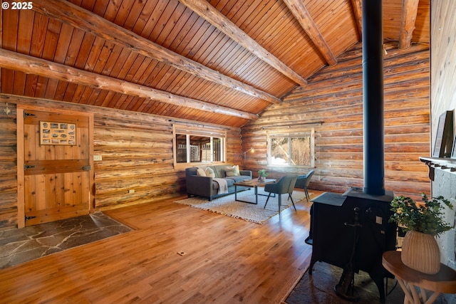 unfurnished living room featuring vaulted ceiling with beams, rustic walls, hardwood / wood-style flooring, wood ceiling, and a wood stove