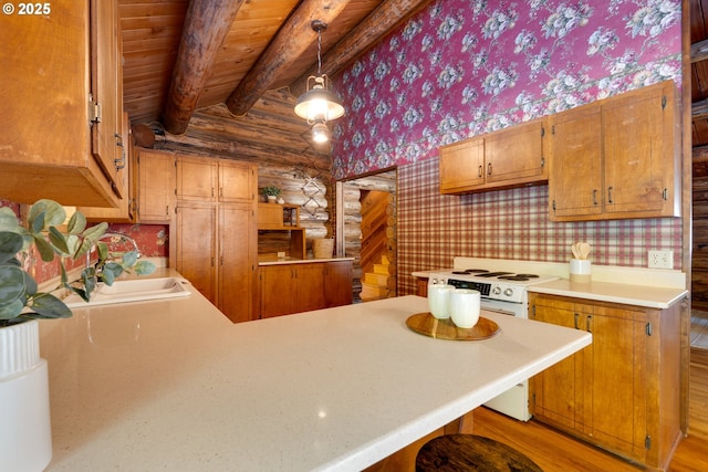 kitchen featuring decorative light fixtures, electric stove, rustic walls, kitchen peninsula, and beam ceiling