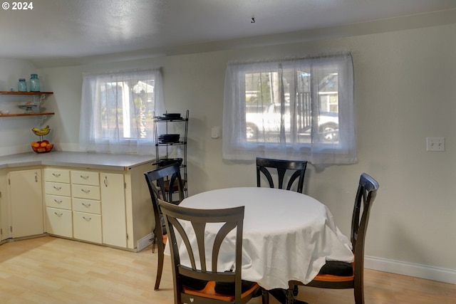 dining space featuring light wood finished floors and baseboards