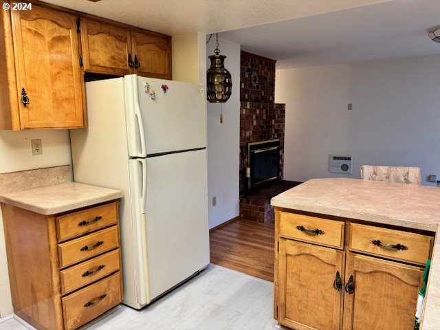 kitchen with white refrigerator, a fireplace, and light hardwood / wood-style flooring