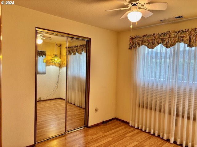 unfurnished bedroom featuring ceiling fan, light hardwood / wood-style floors, and a closet