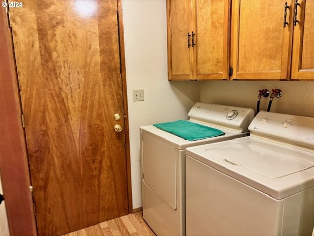 clothes washing area featuring light hardwood / wood-style floors, cabinets, and washing machine and clothes dryer