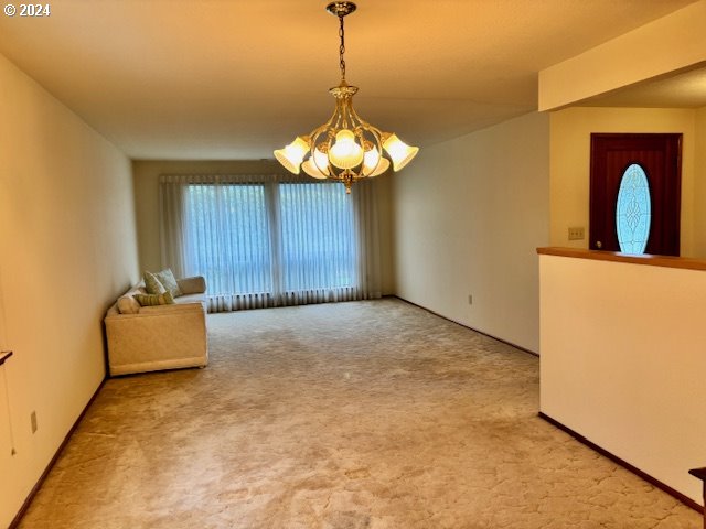 carpeted empty room featuring a notable chandelier