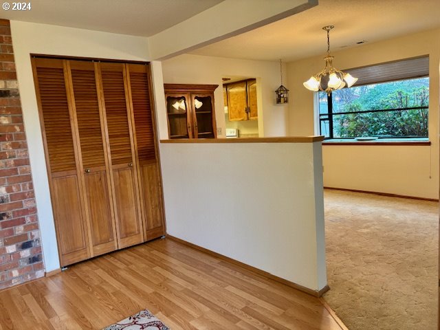 kitchen featuring kitchen peninsula, a chandelier, decorative light fixtures, and light wood-type flooring