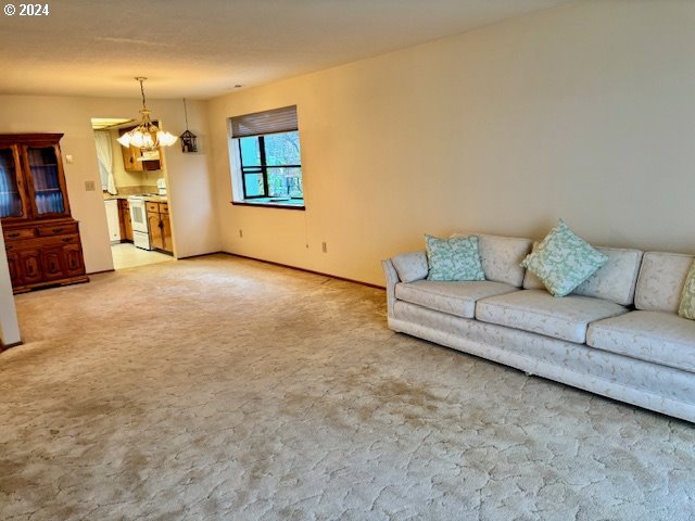 carpeted living room with an inviting chandelier