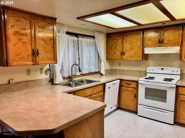 kitchen with kitchen peninsula, white appliances, and sink