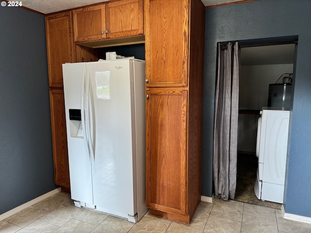 kitchen featuring water heater, washer / clothes dryer, light tile patterned flooring, white refrigerator with ice dispenser, and a textured ceiling