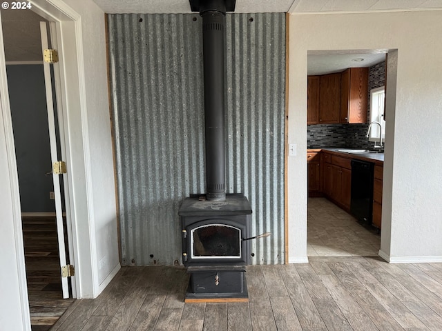 living room with a textured ceiling, sink, light hardwood / wood-style flooring, and a wood stove