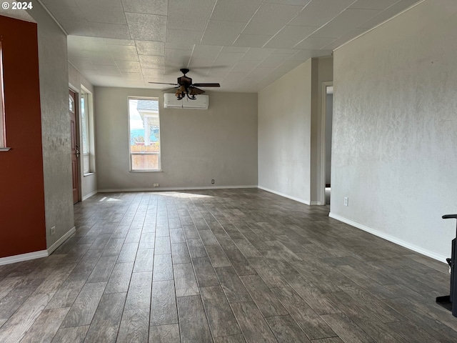 spare room featuring an AC wall unit, ceiling fan, and dark wood-type flooring