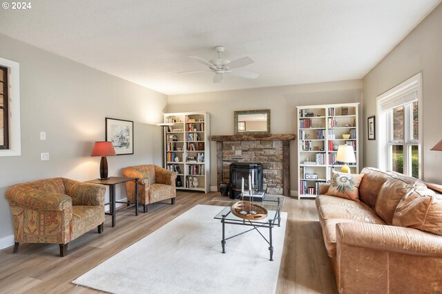 living room with hardwood / wood-style floors, a stone fireplace, and ceiling fan