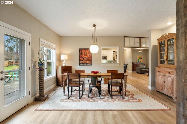 dining area with light wood-type flooring and a textured ceiling