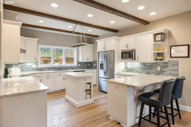 kitchen with beam ceiling, white cabinetry, stainless steel appliances, kitchen peninsula, and a kitchen island