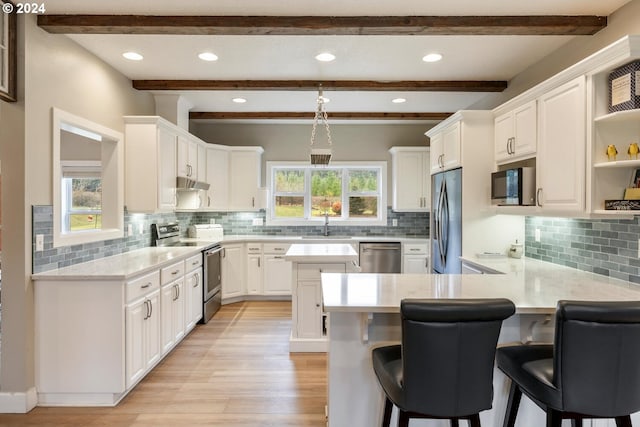 kitchen featuring white cabinetry, kitchen peninsula, decorative backsplash, a breakfast bar, and appliances with stainless steel finishes