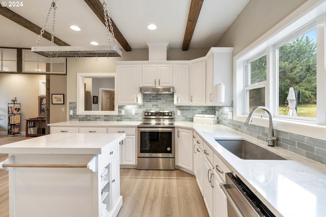 kitchen featuring appliances with stainless steel finishes, a kitchen island, sink, beamed ceiling, and white cabinetry