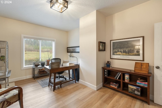 home office with a textured ceiling and light hardwood / wood-style flooring