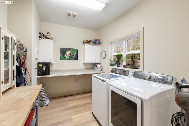 washroom featuring separate washer and dryer, cabinets, and light wood-type flooring