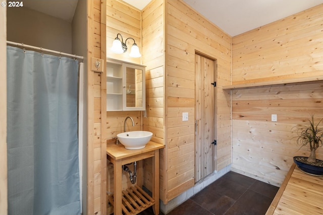 bathroom with tile patterned flooring, a shower with curtain, sink, and wood walls