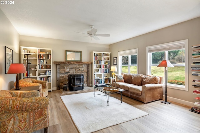 living room featuring ceiling fan, a wood stove, and light hardwood / wood-style flooring