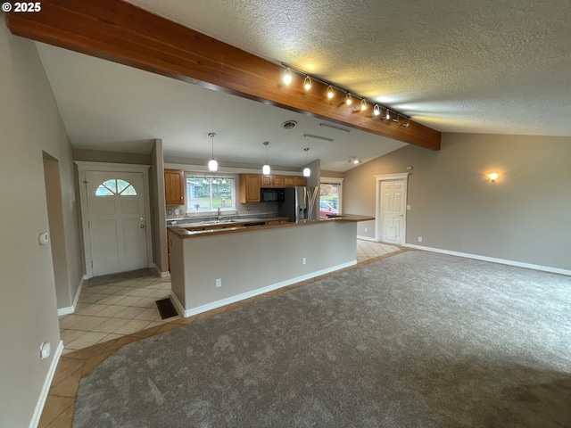 kitchen featuring stainless steel fridge, a textured ceiling, track lighting, lofted ceiling, and light tile patterned floors